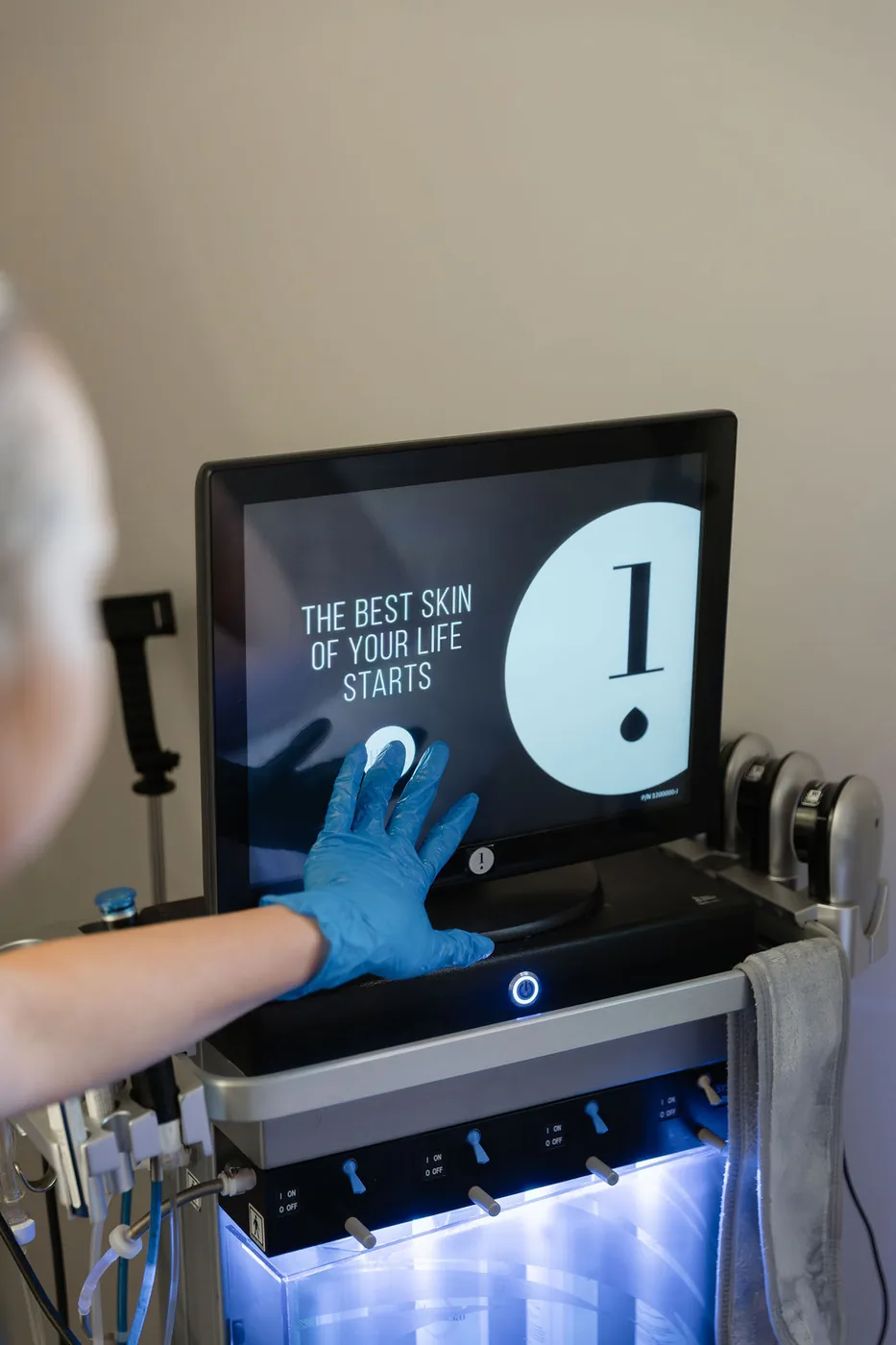 Therapist starting the Hydrafacial machine at The Skin Lounge Bristol, screen reading: the best skin of your life starts here